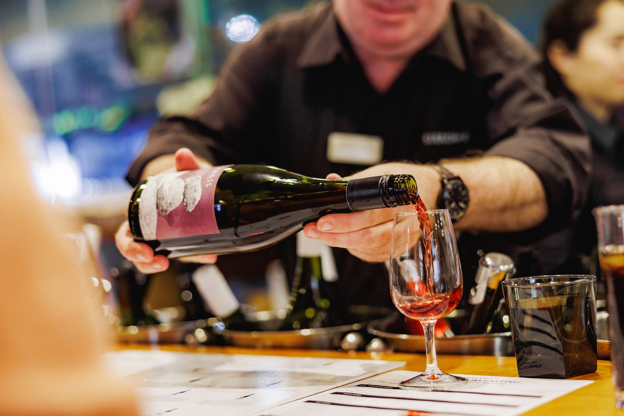 Male staff member pouring glass of red wine