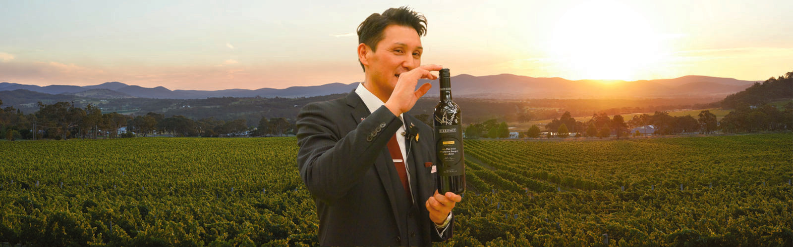 Japanese man at Sirromet holding wine bootle in front of vineyard