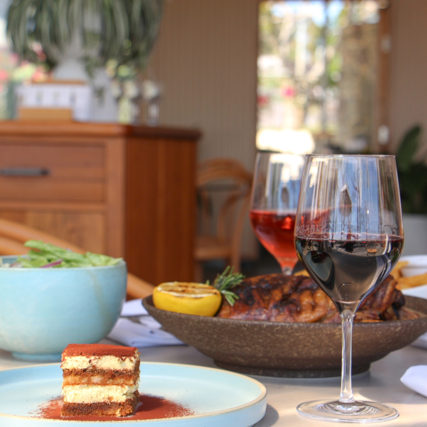 Dinner setting with wine, salad, and dessert on a table.