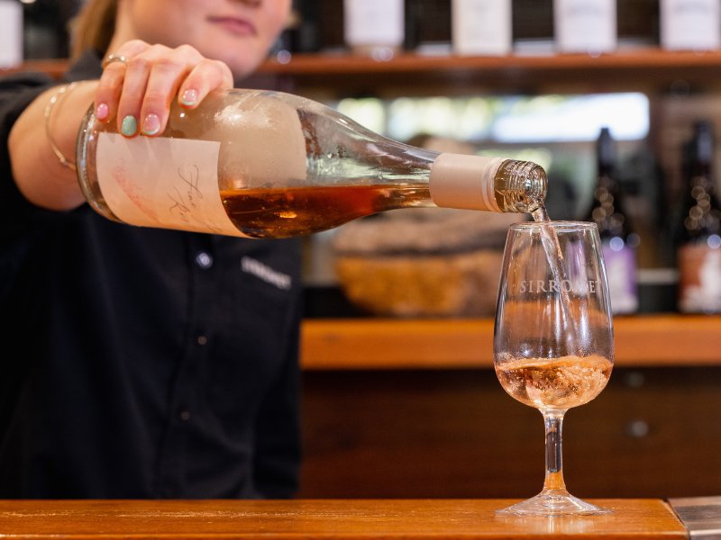 Sirromet staff member pouring a glass of white wine