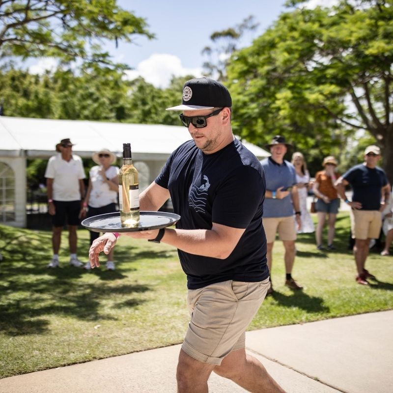 Male holding wine bottle on a tray during winery sporting games contest