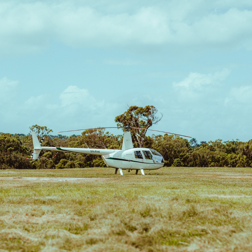 Helicopter on a grassy field with trees in the background