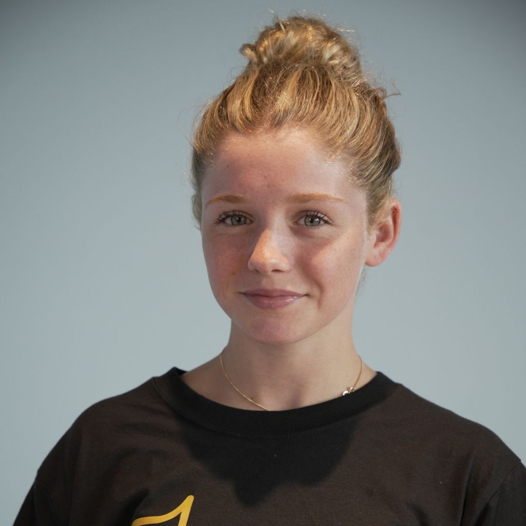 Maggie Grey wearing a black shirt with a logo on a gray background