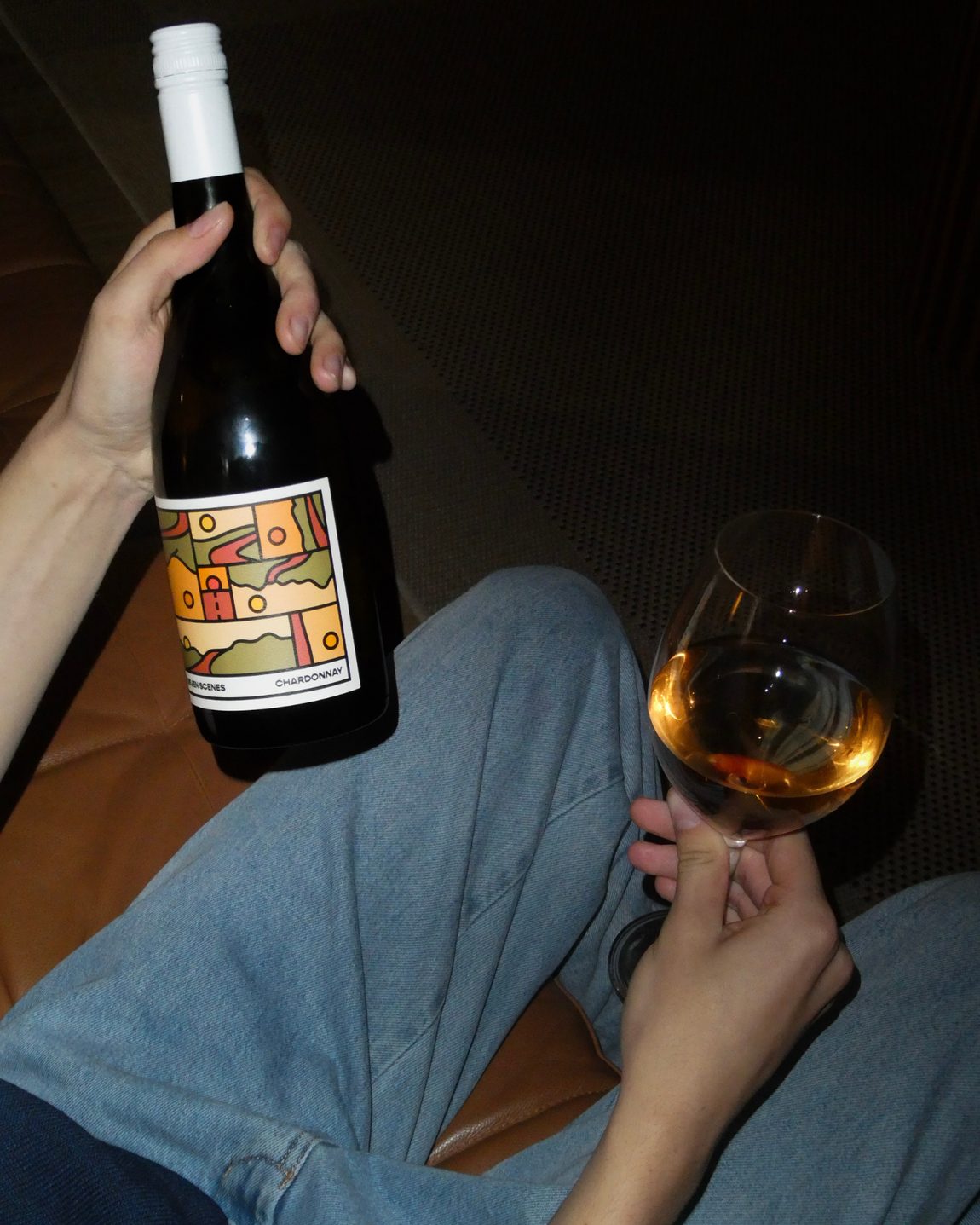 A member on the couch with a bottle of Sirromet chardonnay and a glass