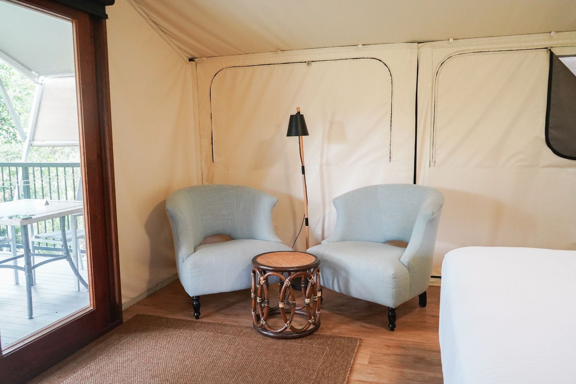 Interior of a glamping tent with two chairs, a table, and a lamp.
