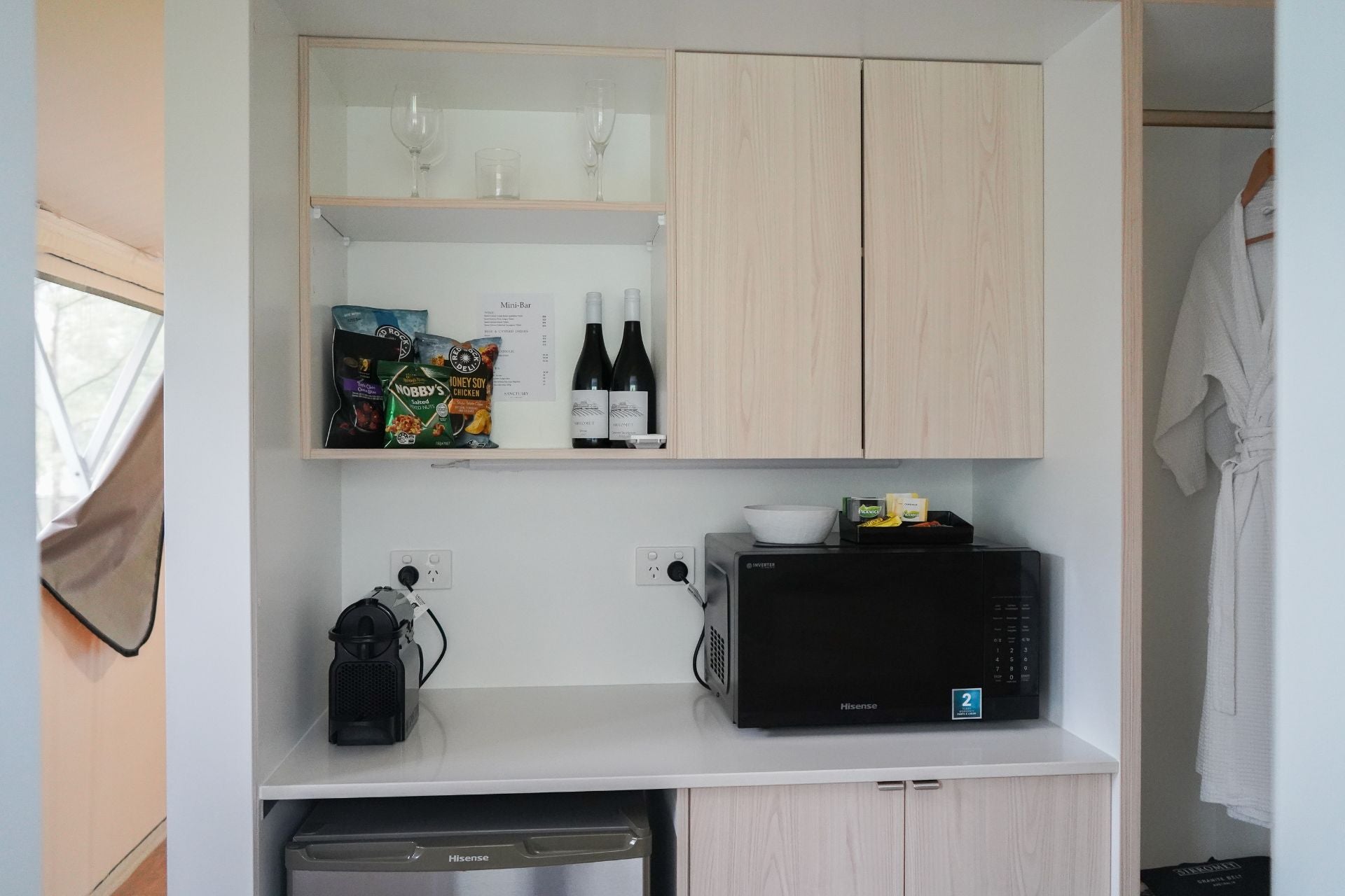 Small kitchenette with microwave, coffee maker, and snacks in a compact space inside a glamping  tent