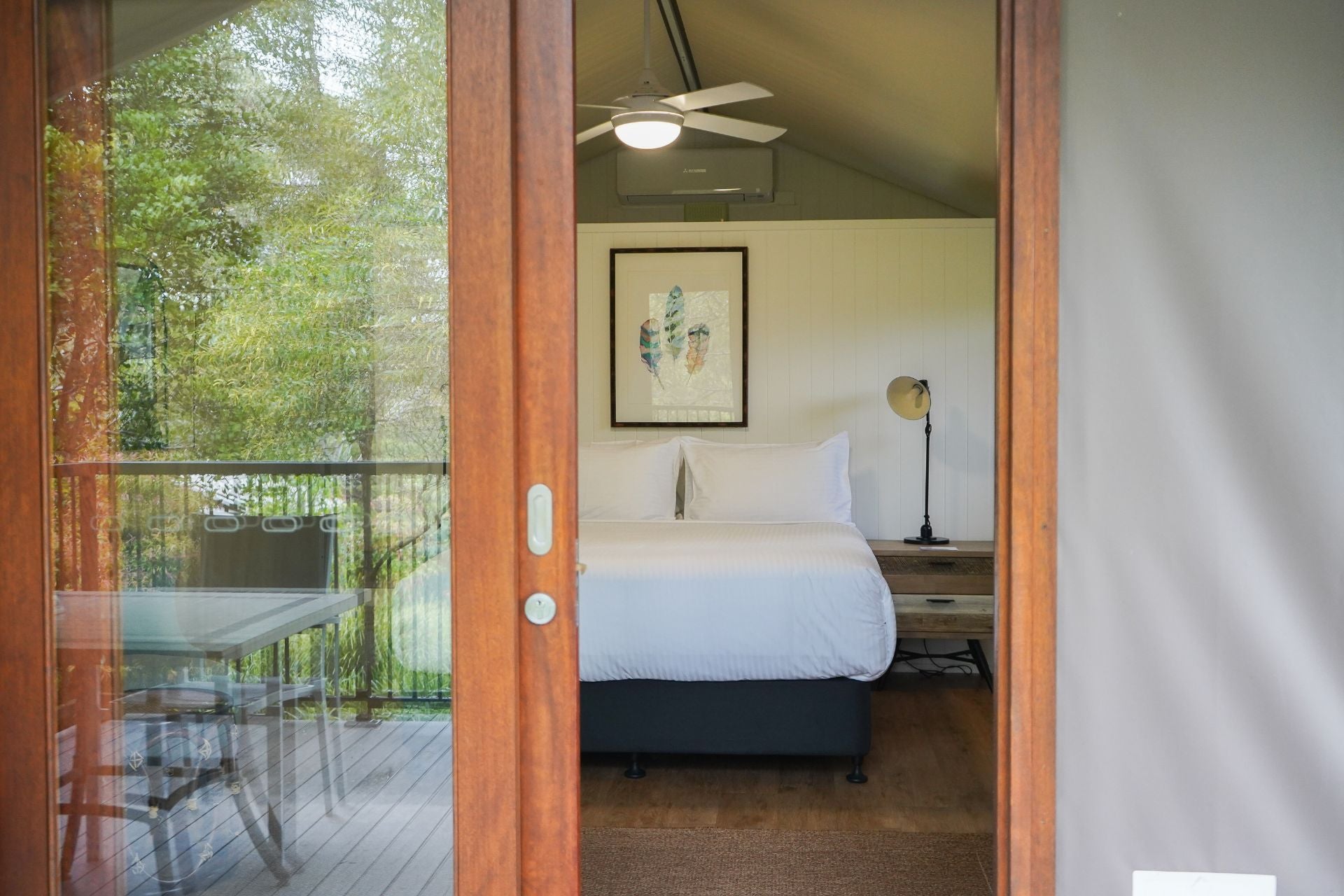 Bedroom with a view of a tree outside through a glass door of a glamping tent.