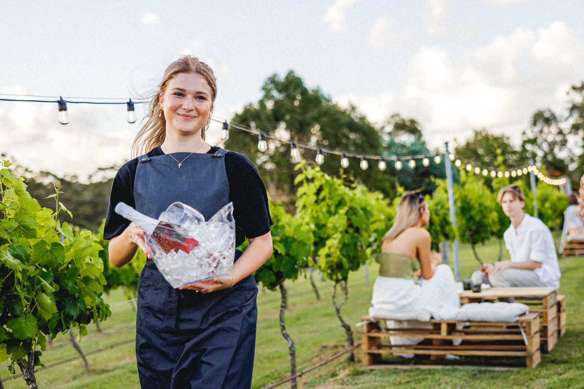 Wine waitress holding an ice bucket and wine in the Sirromet garden area