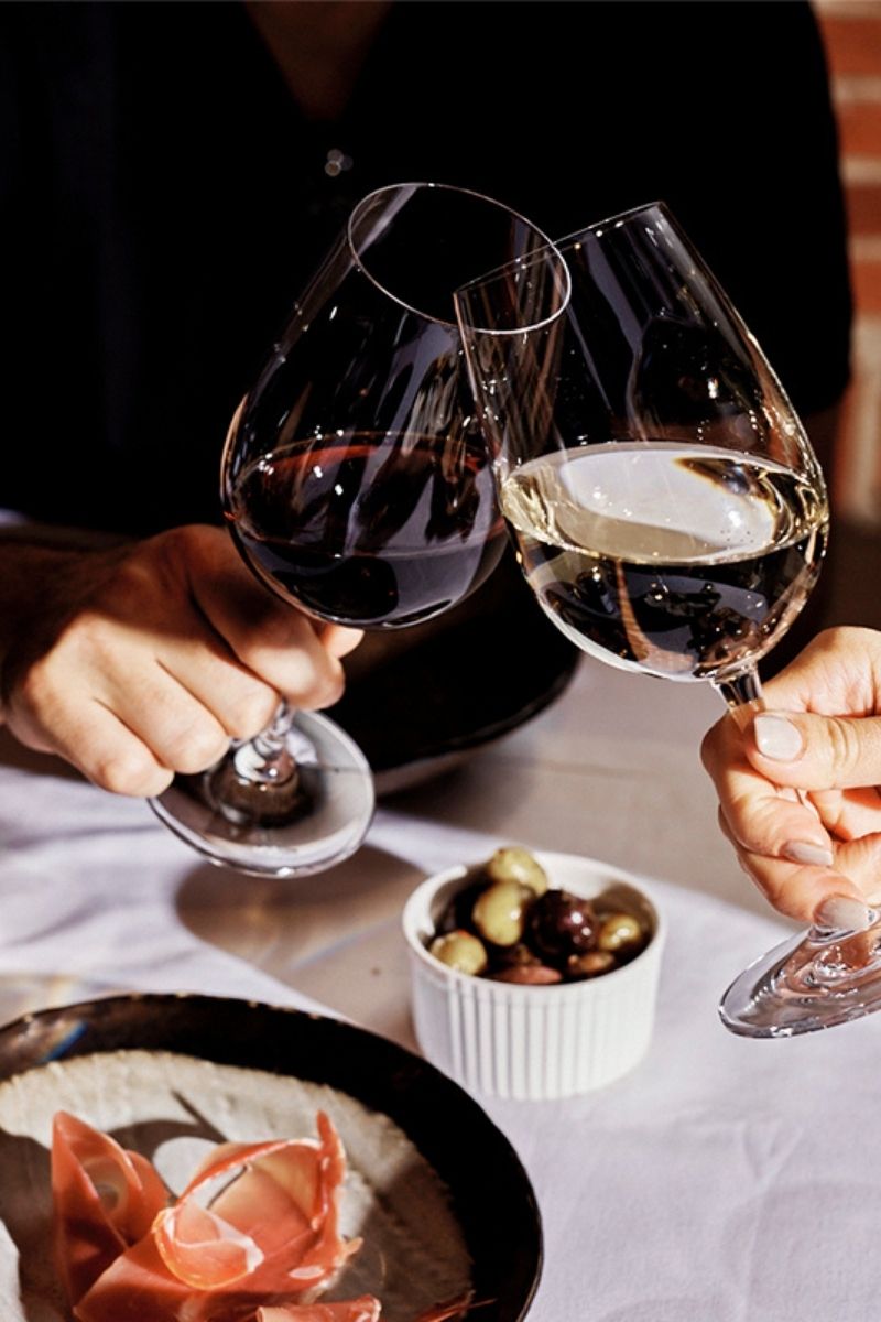 Glass of red and white wine being "cheers"
