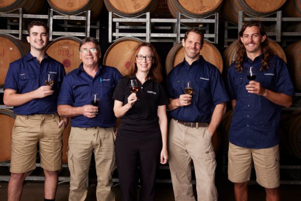 Sirromet winemakers standing in front or a row of wine barrels