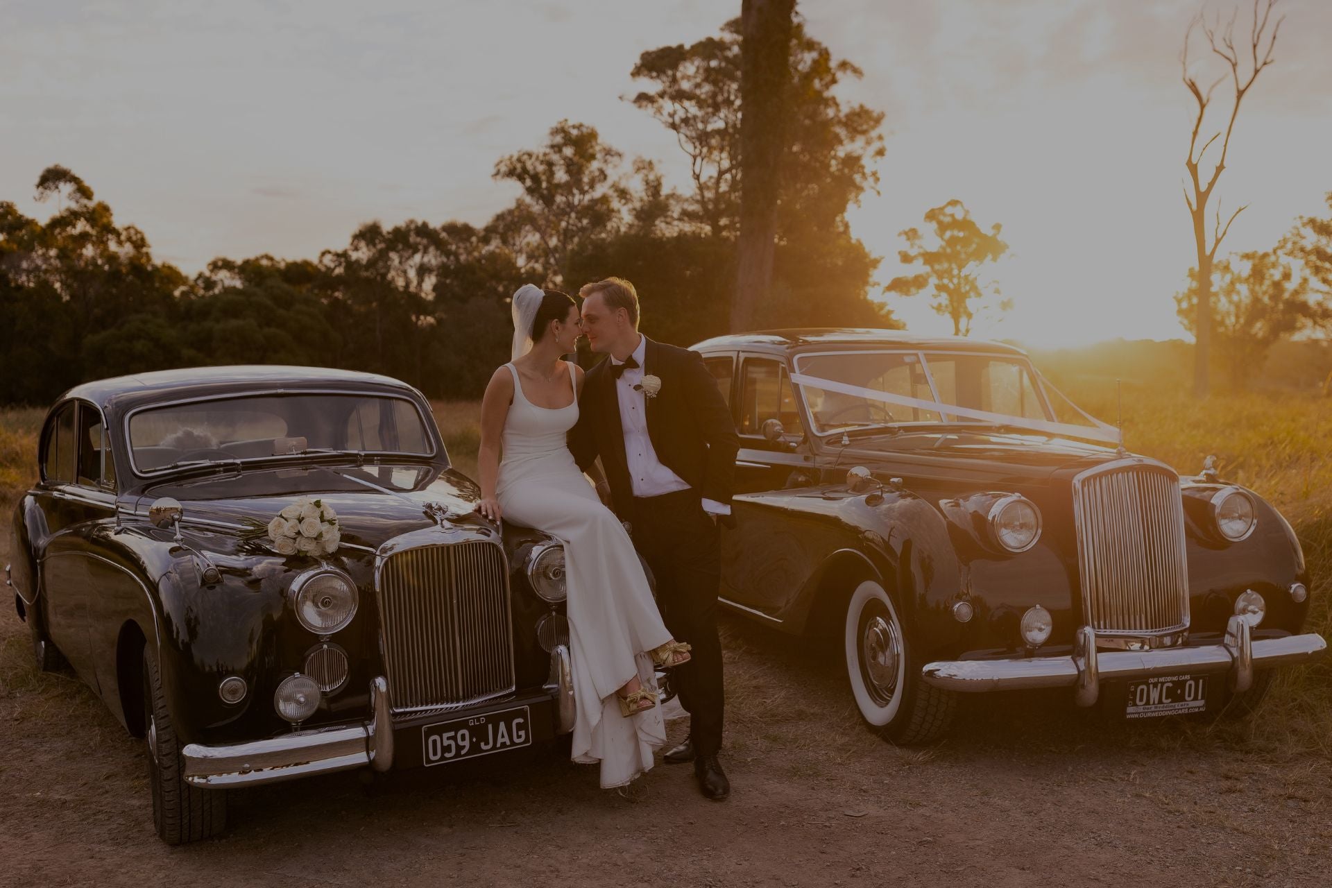 Bride, groom and two wedding cars in the sunset