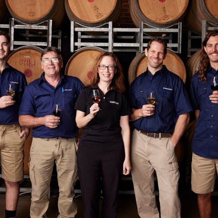 Sirromet winemakers in front of row of wine barrels