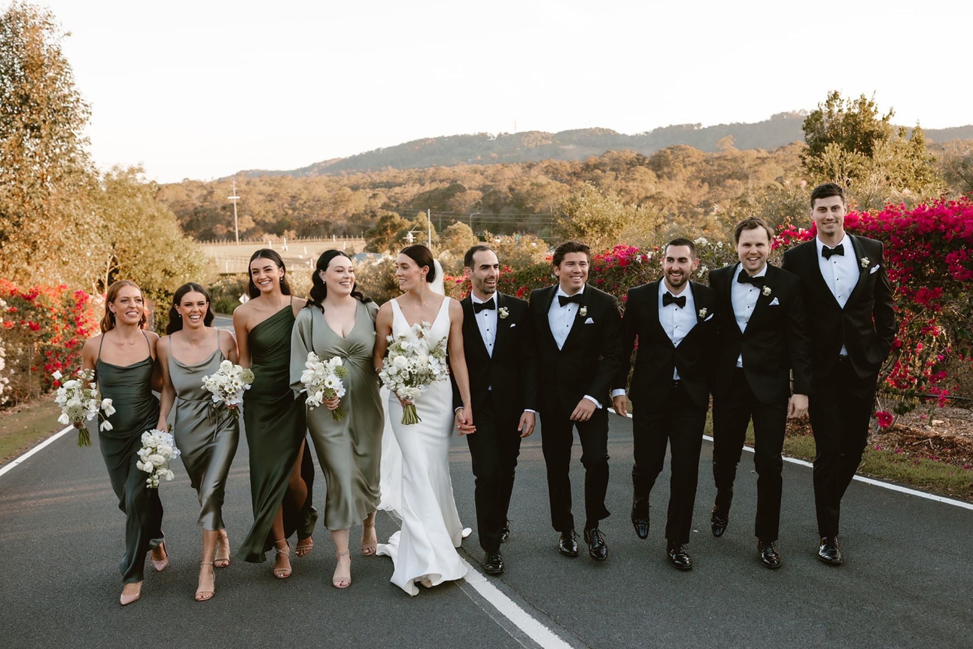 Bride, groom and wedding party walking next wine vineyard at Sirromet